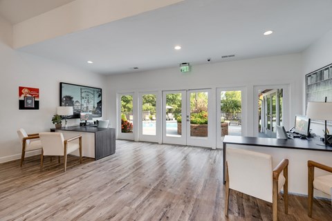 a living room with a desk and chairs and sliding glass doors